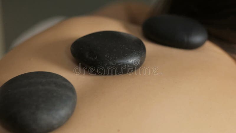 Закройте вверх молодой женщины делая каменную терапию с горячими камнями
